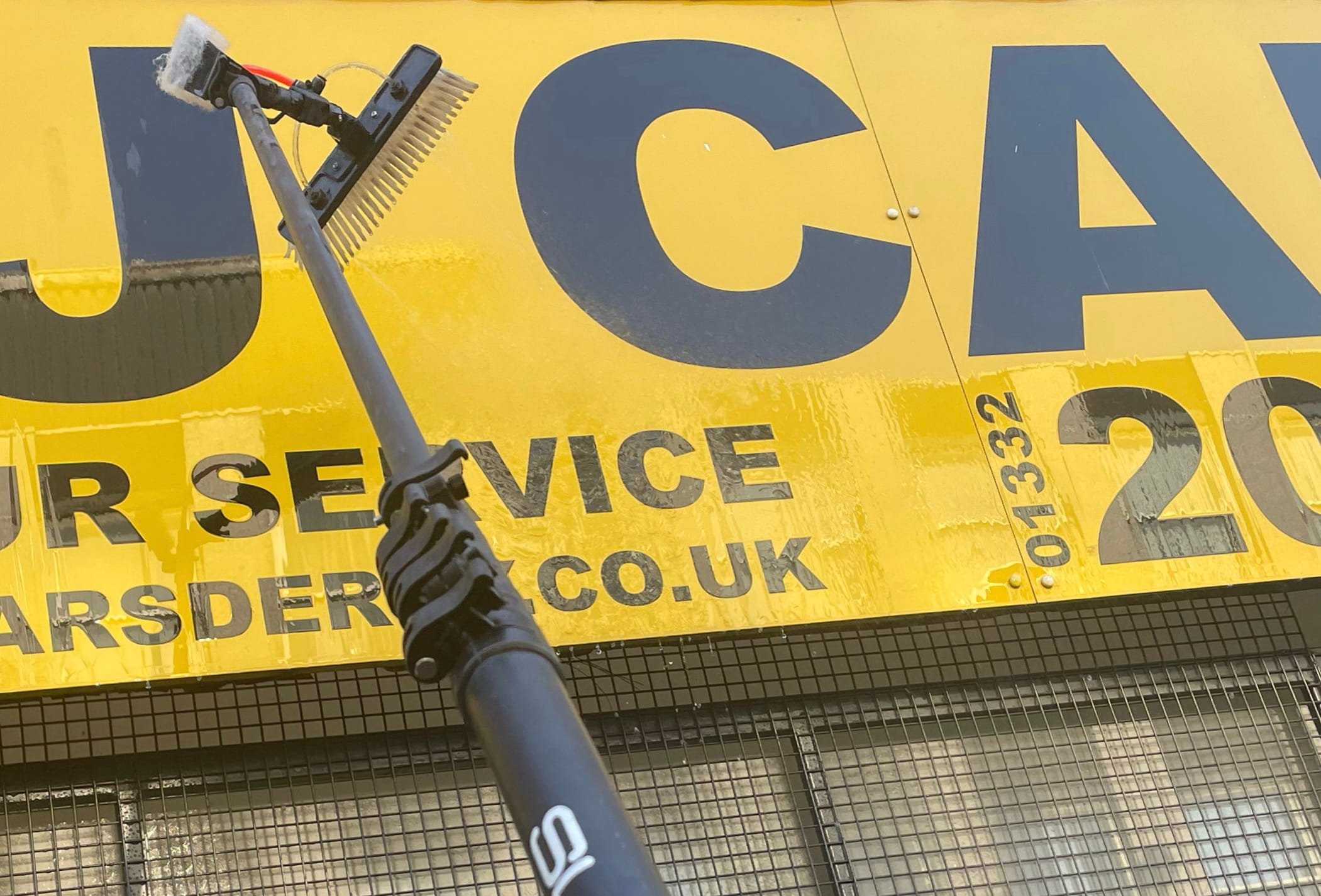 Fast and Clean operative using a water-fed pole to clean a large commercial sign on a shop front in Derby