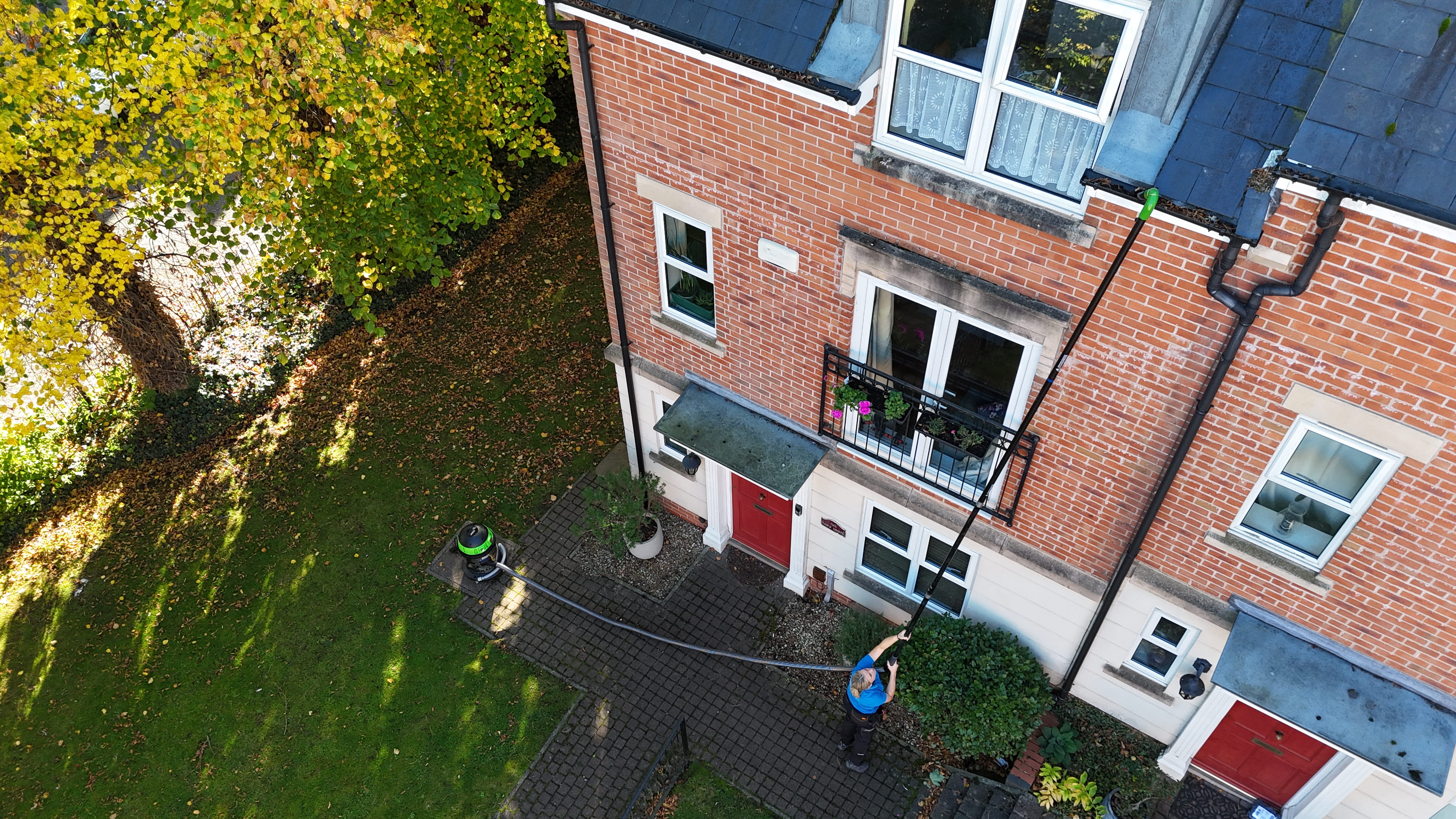 Aerial drone shot of gutter cleaning in progress on a tall Victorian red brick building