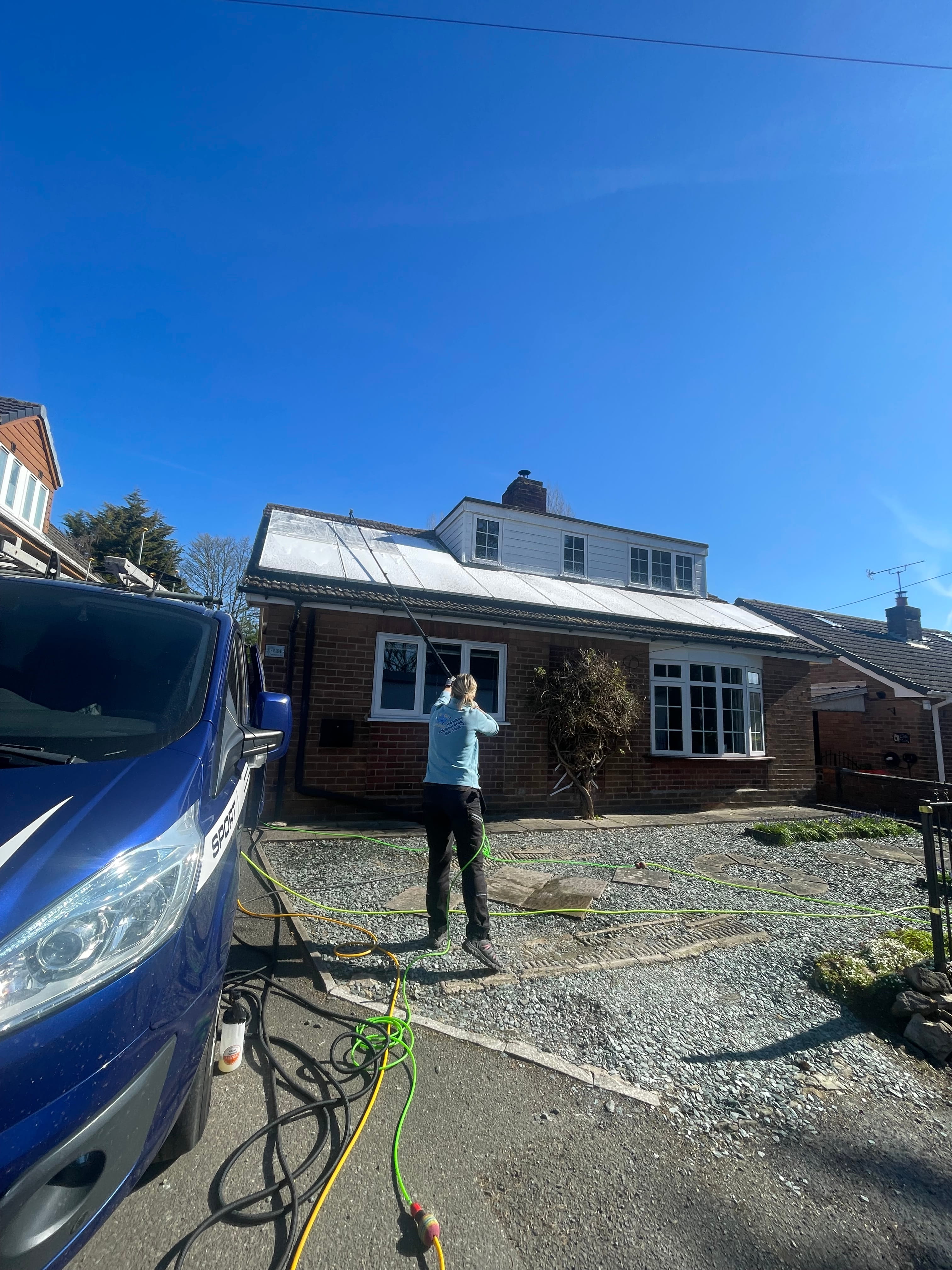 Solar panel cleaning in progress on a bungalow roof, Fast and Clean van visible